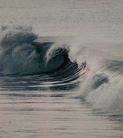 a large wave crashes into the shore of the ocean