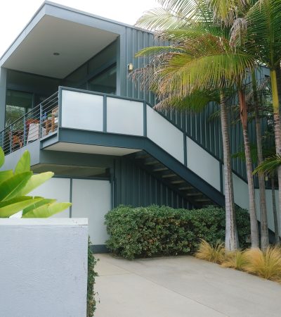 a building with a balcony and palm trees in front of it