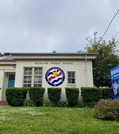 front of white brick school and lawn
