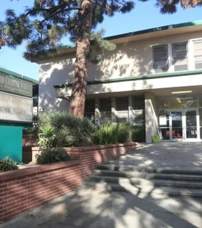 white two story brick school and green sign