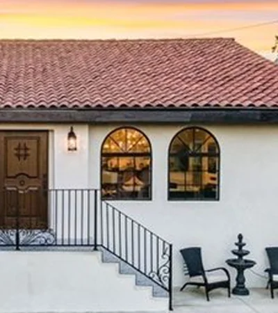a white house with a black railing and chairs