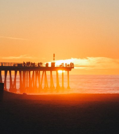 silhouette of dock on body of water during sunset