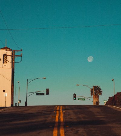 an empty street with a stop light and palm trees