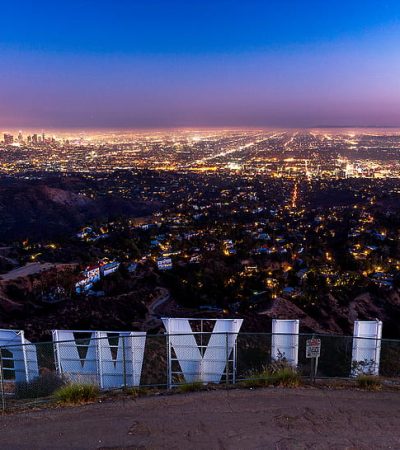 a sign on a hill with a city in the background