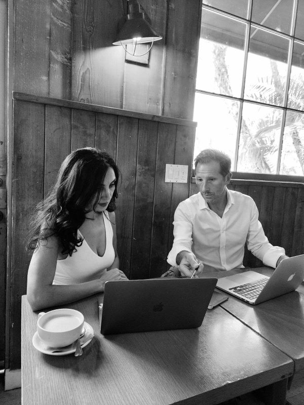 a man and woman sitting at a table with laptops