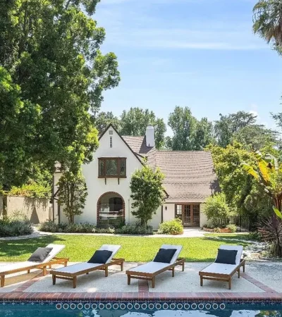 a pool with lounge chairs in front of a house