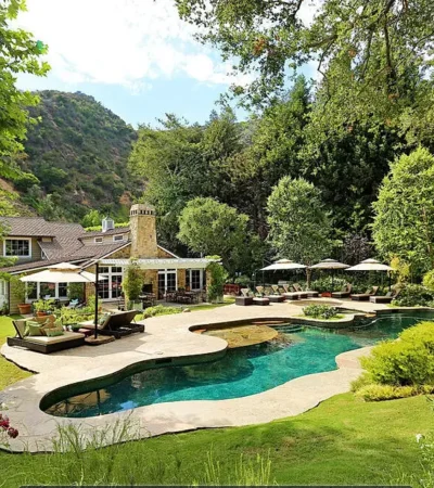 a pool and a house with trees and a hill in the background