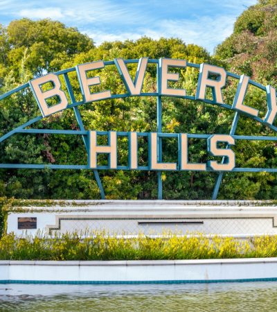 a sign that says beverly hills in front of a body of water