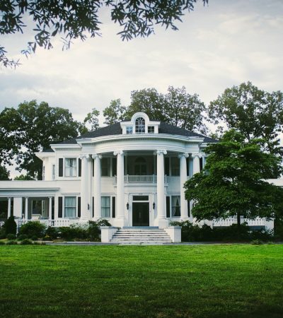 white and gray concrete house surrounded by grass and trees